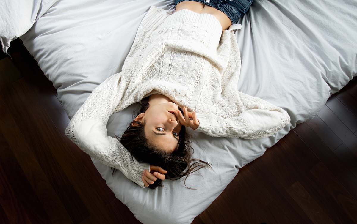 person woman lying on bed with white bedspread human