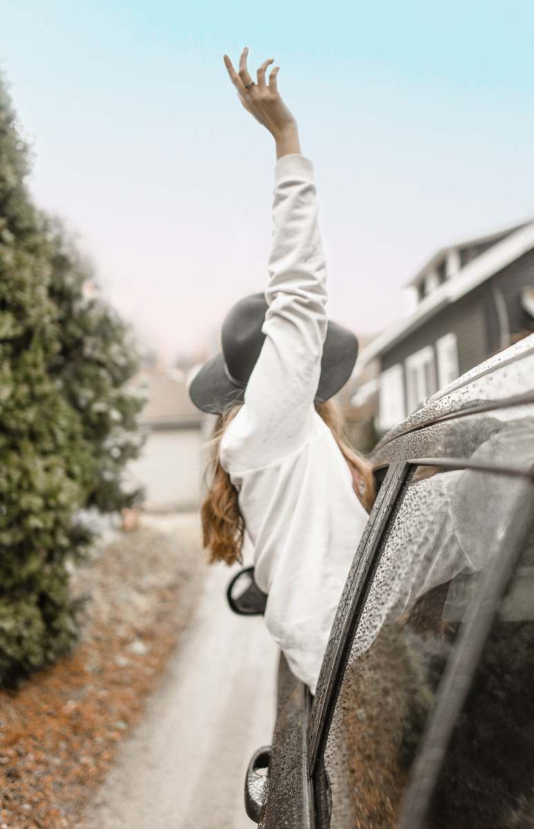 human woman rising left hand on vehicle window during daytime person
