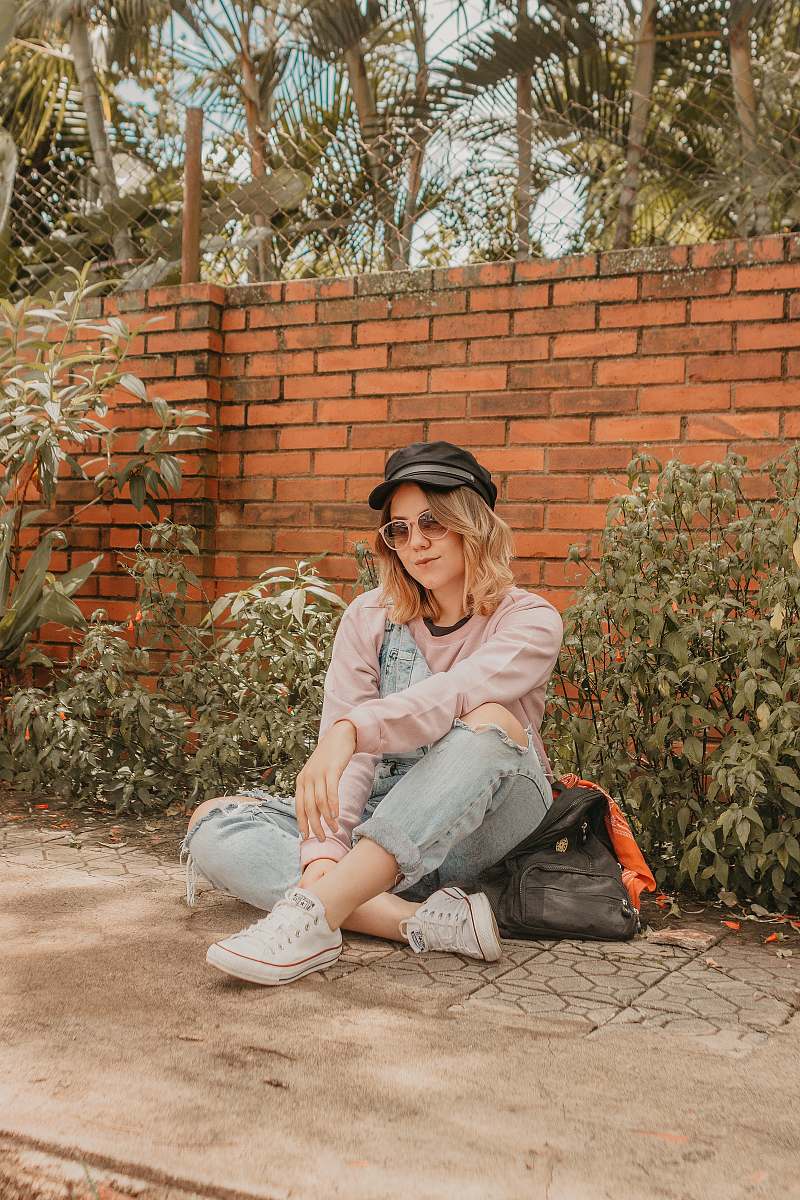 person woman sitting down on gray concrete slab near brick wall human