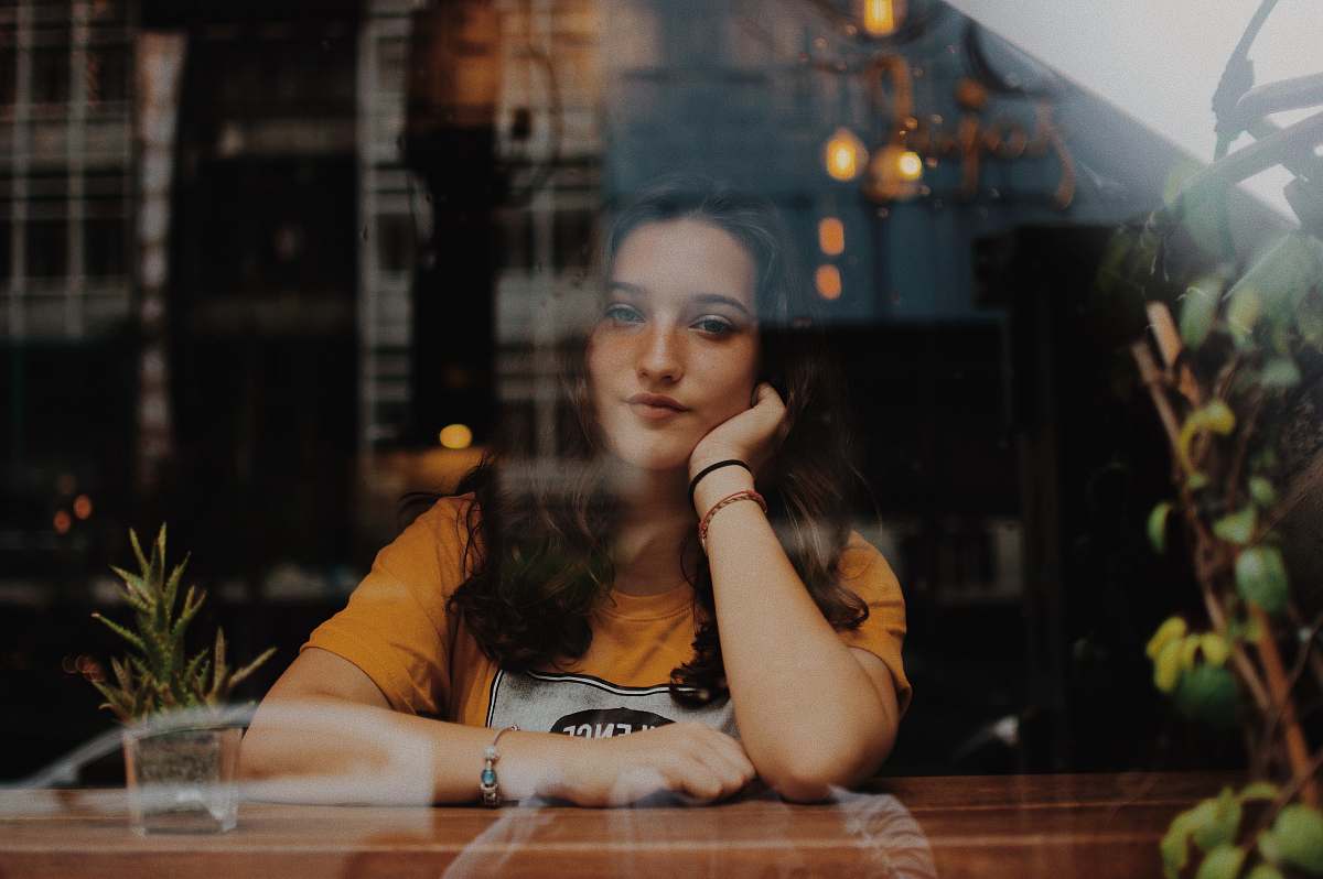 human woman sitting next to table with hands on cheek person