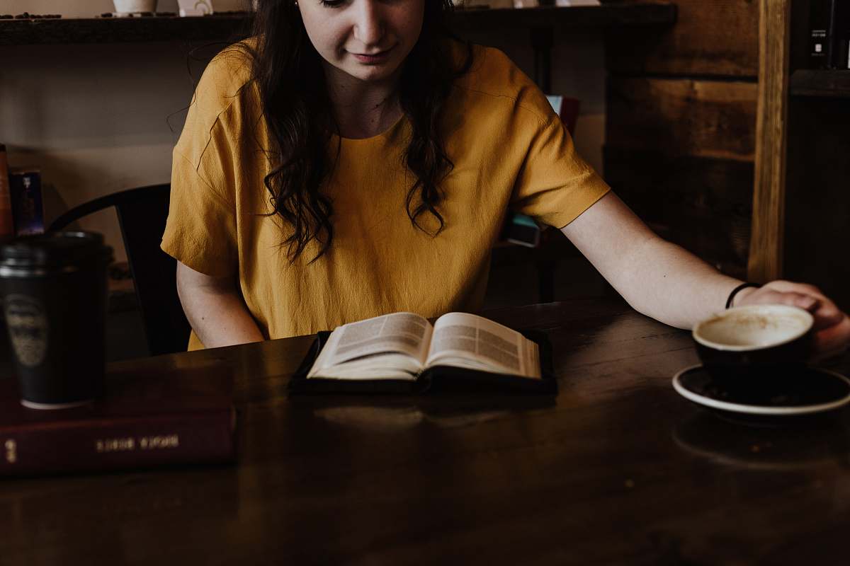 person woman sitting on chair in front of book reading