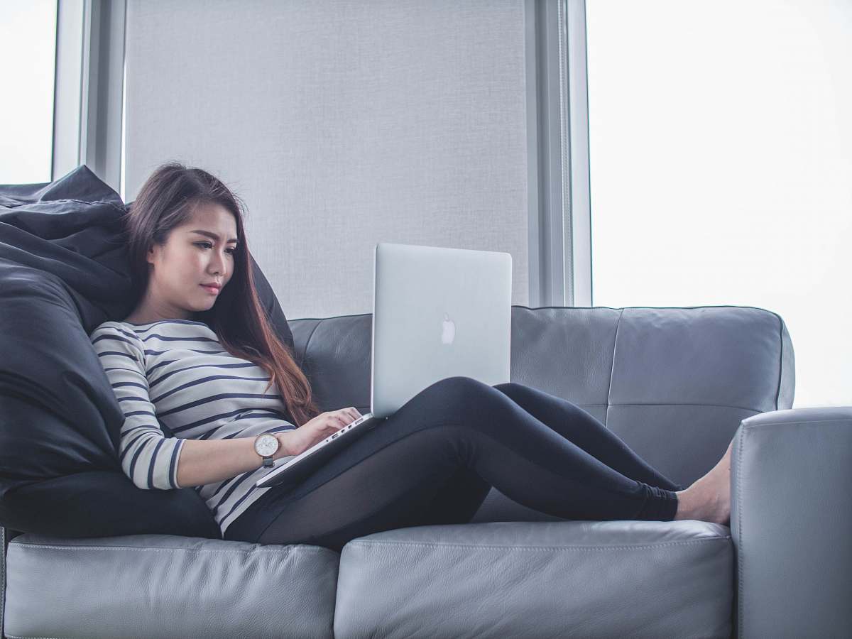 person woman sitting on sofa while using MacBook Pro computer