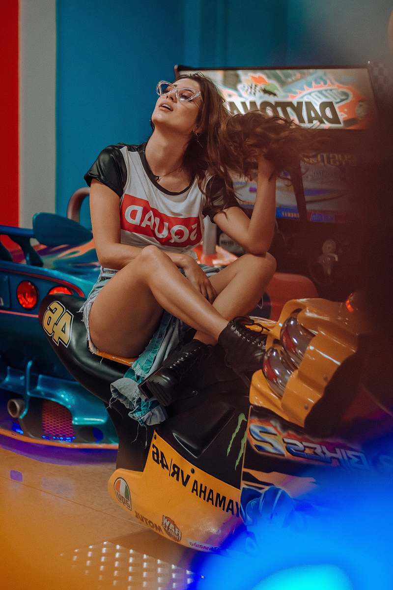 human woman sitting on yellow and black Yamaha VR 46 Valentino Rossi arcade machine inside well lighted room person