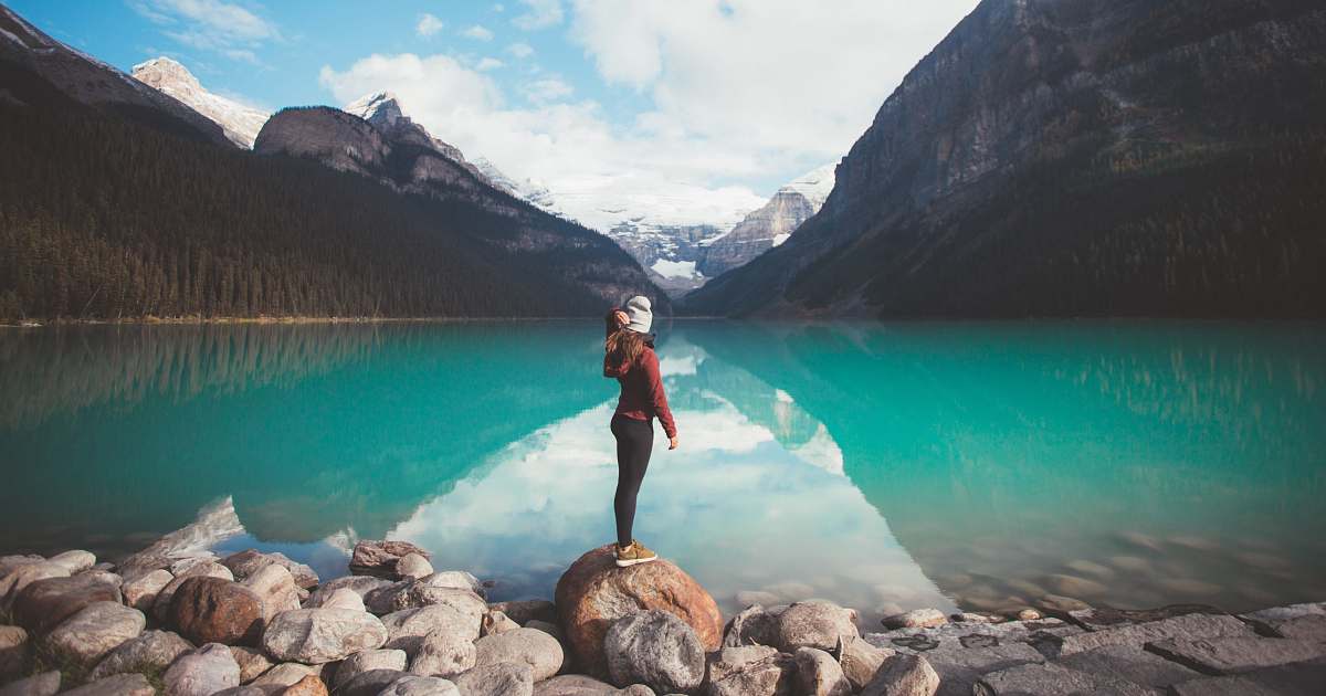 mountain woman standing on brown rock taken at daytime snow