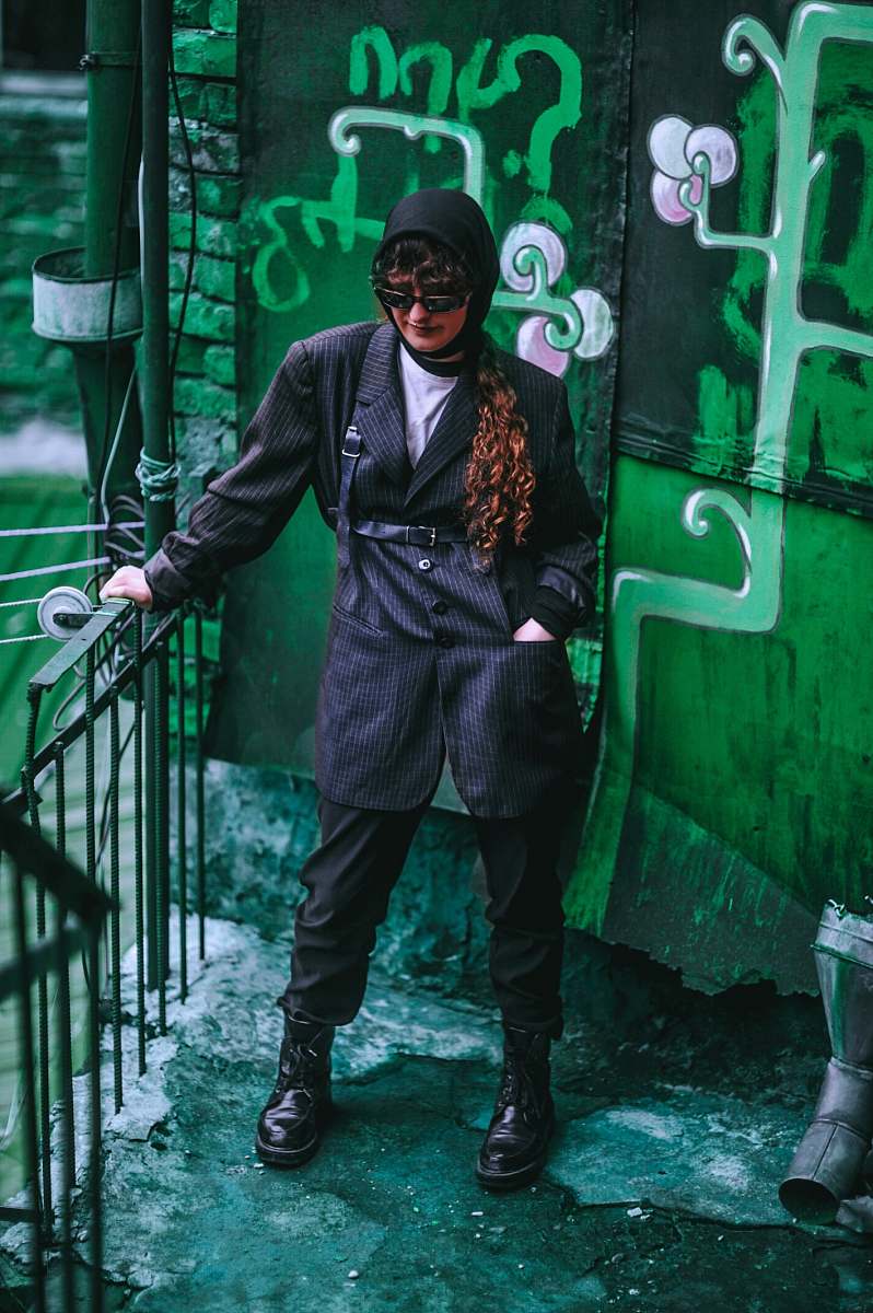 human woman standing on corner holding metal rail person
