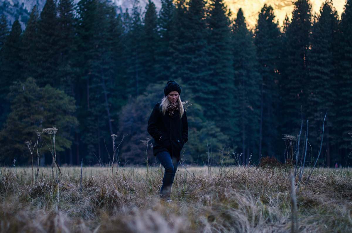human woman standing on grass field near tall trees person