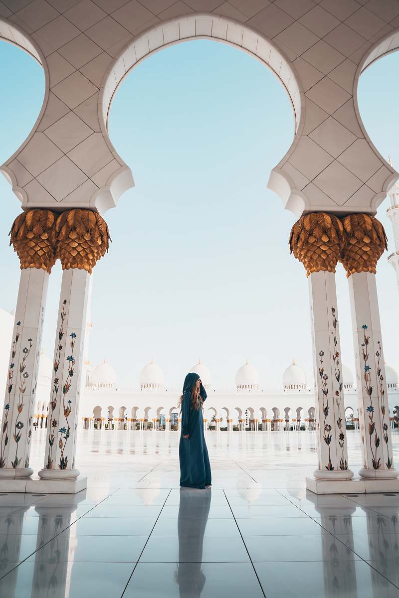 person woman standing on white tiled floor in the middle of concrete pillars building
