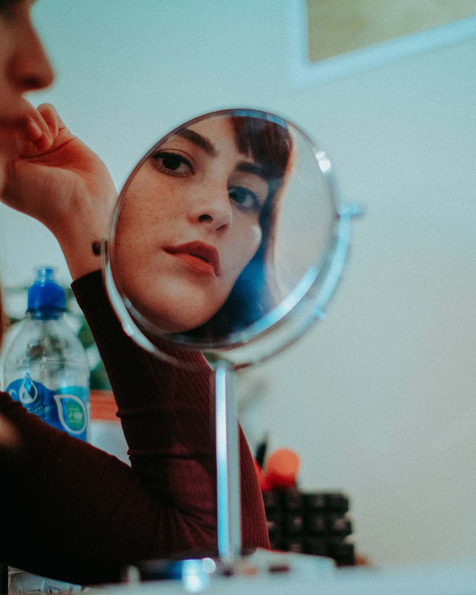 person woman staring at round mirror with silver frame human