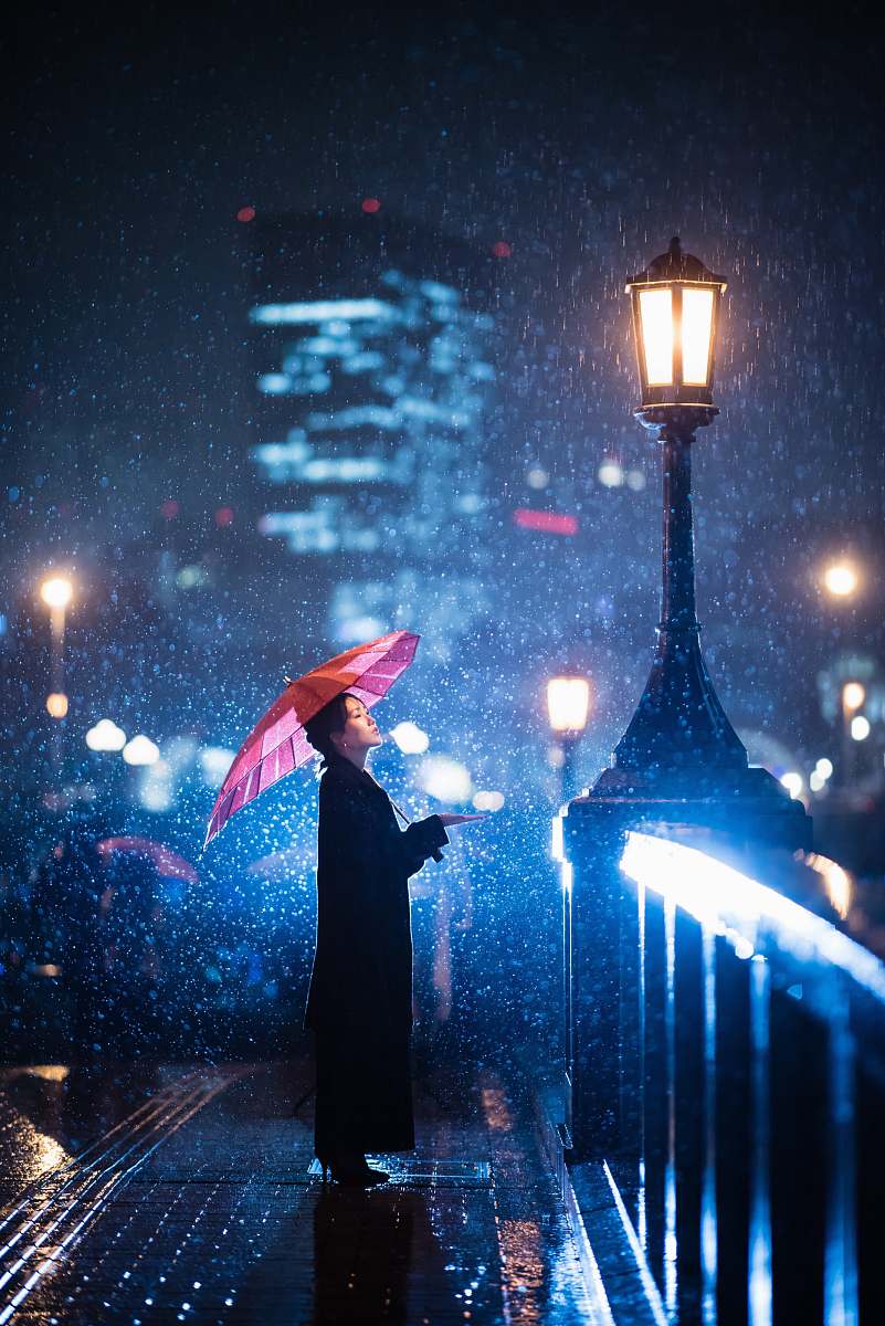 person woman using umbrella standing near bridge light post human