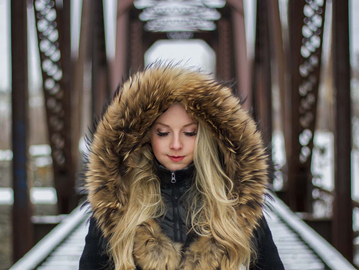 human woman wearing brown fur-lined hoodie standing on the bridge during daytime photography person