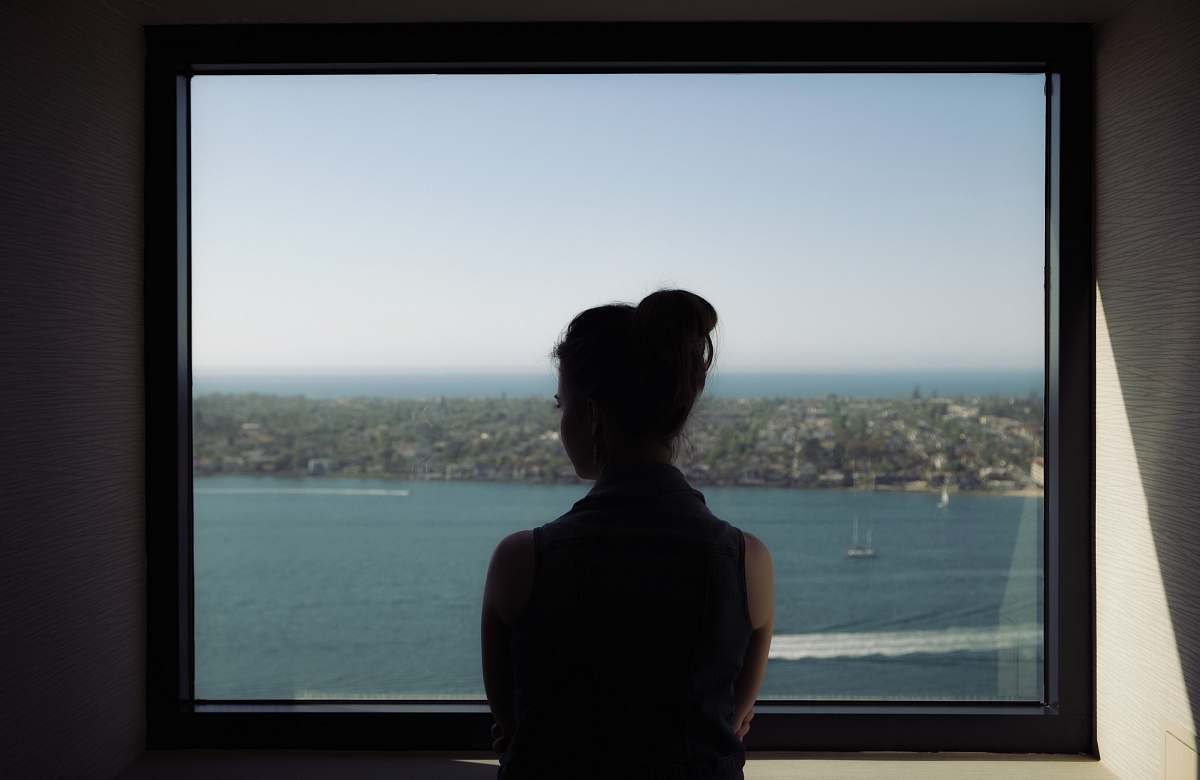 person woman wearing off-shoulder shirt standing beside window human