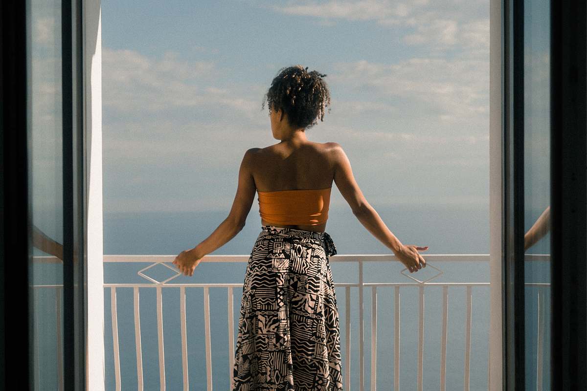 human woman wearing orange tube and black skirt facing terrace person