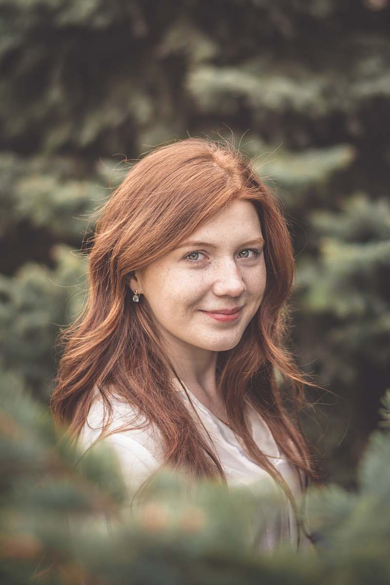 person woman wearing white crew-neck shirt behind trees during daytime human