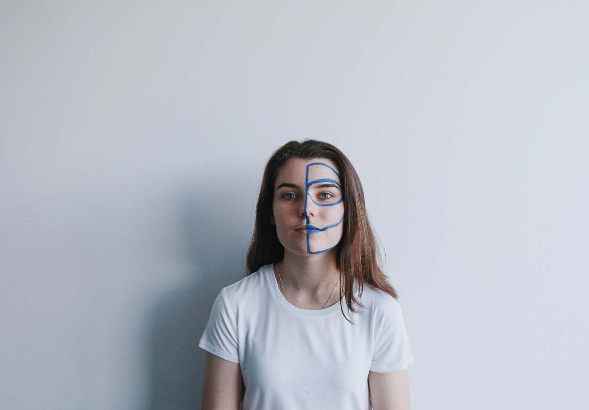 human woman wearing white crew-neck t-shirt with mask on face leaning on wall person