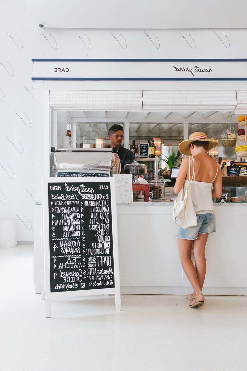 human woman with white spaghetti strap top near the bar person