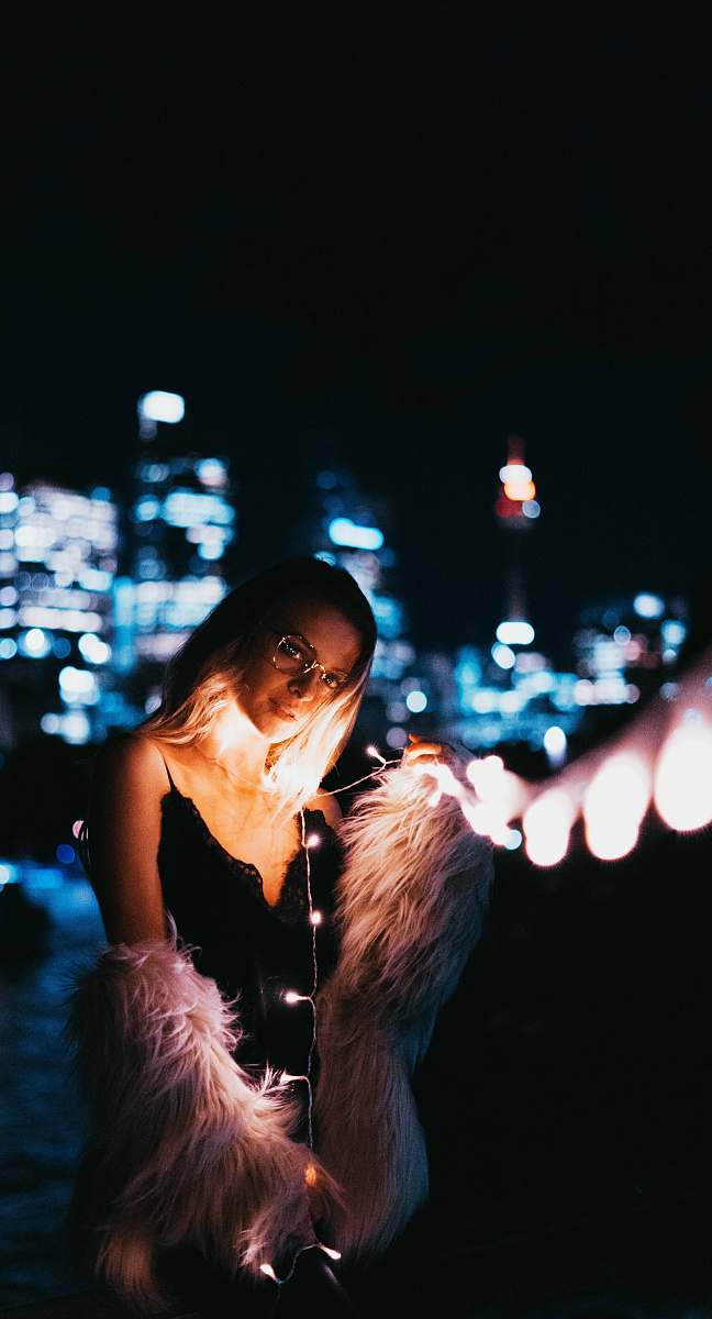 human woman's in black dress holding white string lights person