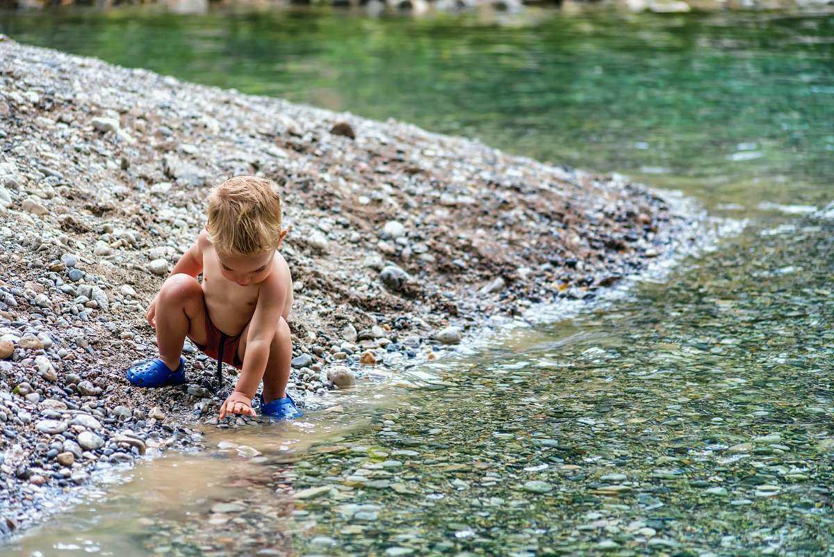 human baby playing beside body of water people