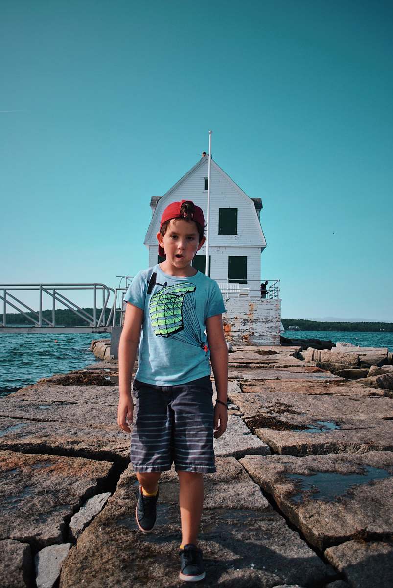 human boy standing near white house beside body of water people