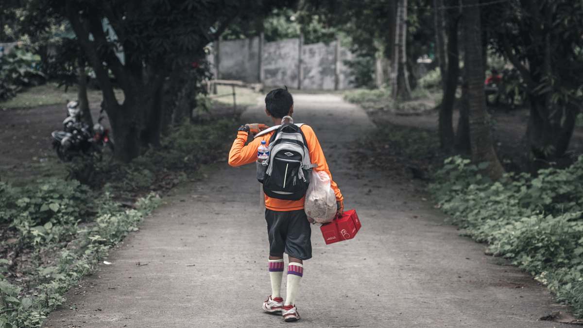 people boy with backpack walking on pathway between trees human