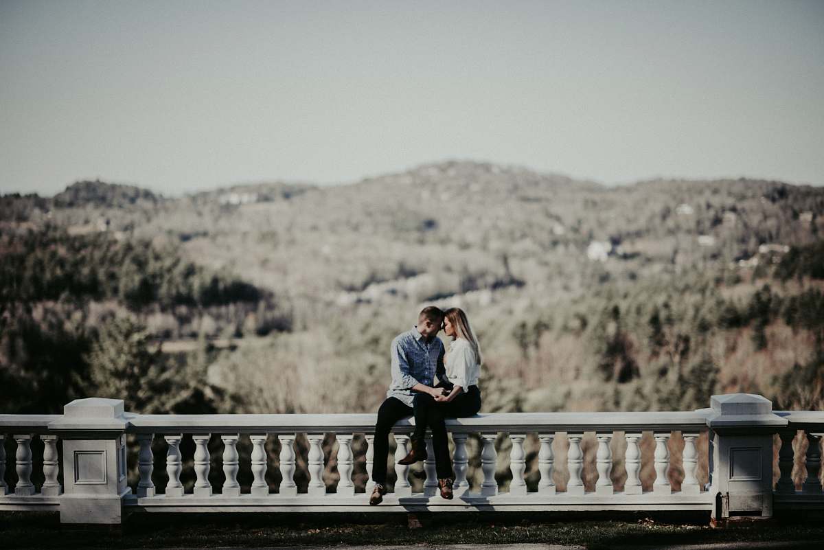 human couple sitting on ledge in distant of mountain people