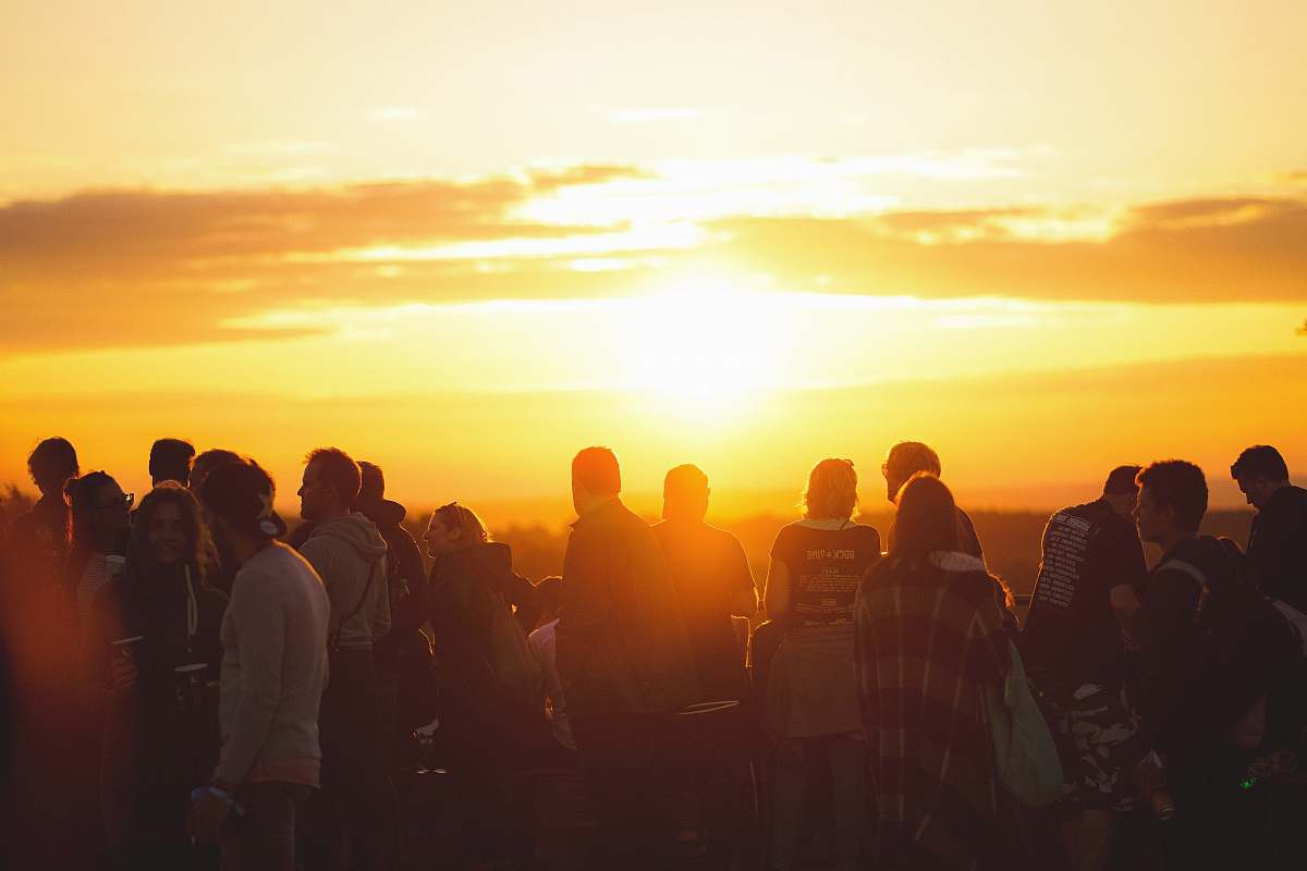 people crowd of people standing and walking during sunset human