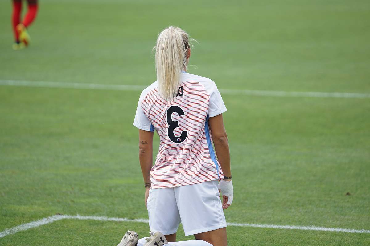 human female soccer player standing at field people