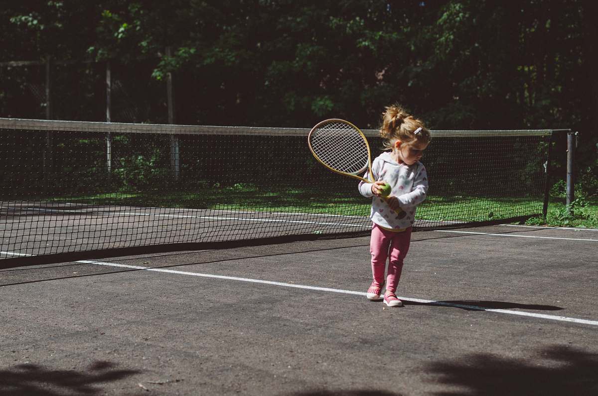 people girl holding lawn tennis racket while standing beside white and black net human