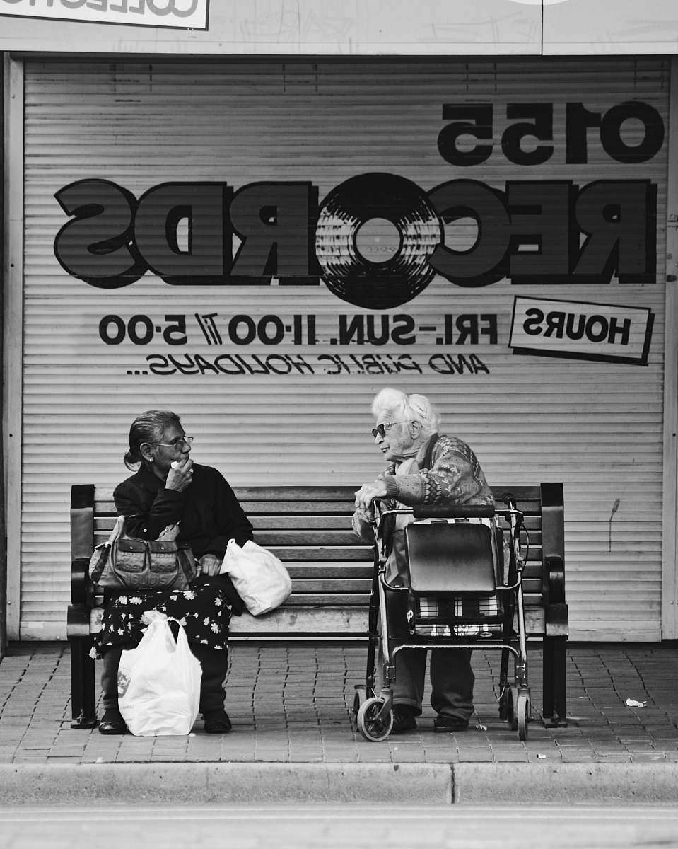 human grayscale man and woman sitting on bench black-and-white