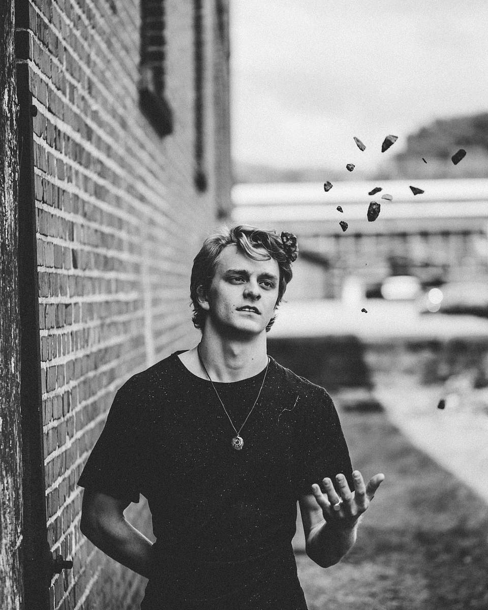 human grayscale photo of man standing beside the wall black-and-white