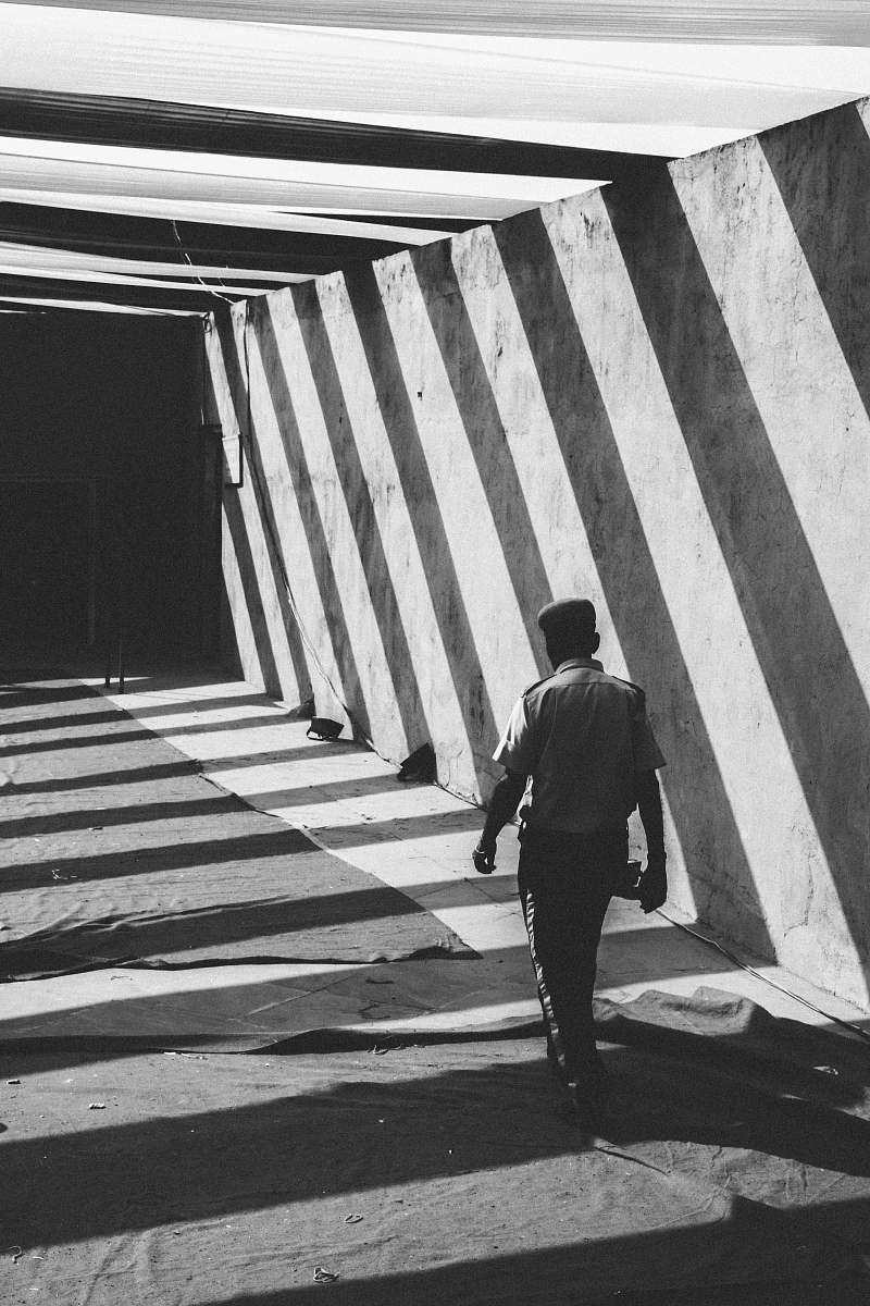 people grayscale photo of man walking towards gate black-and-white