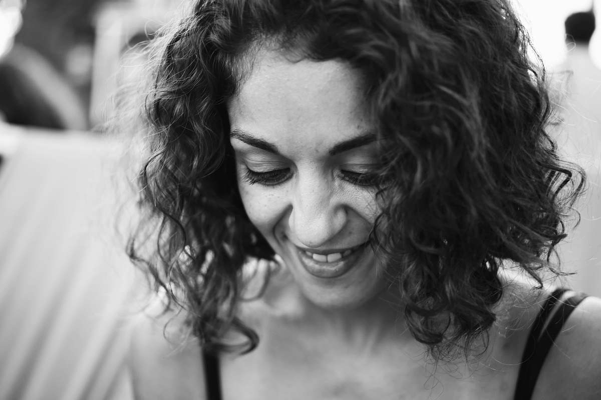 human grayscale photo of smiling woman wearing spaghetti strap top black-and-white
