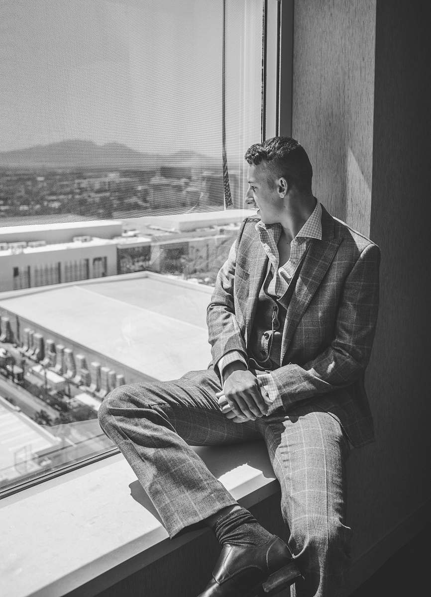 black-and-white grayscale photography of man sitting on window grey