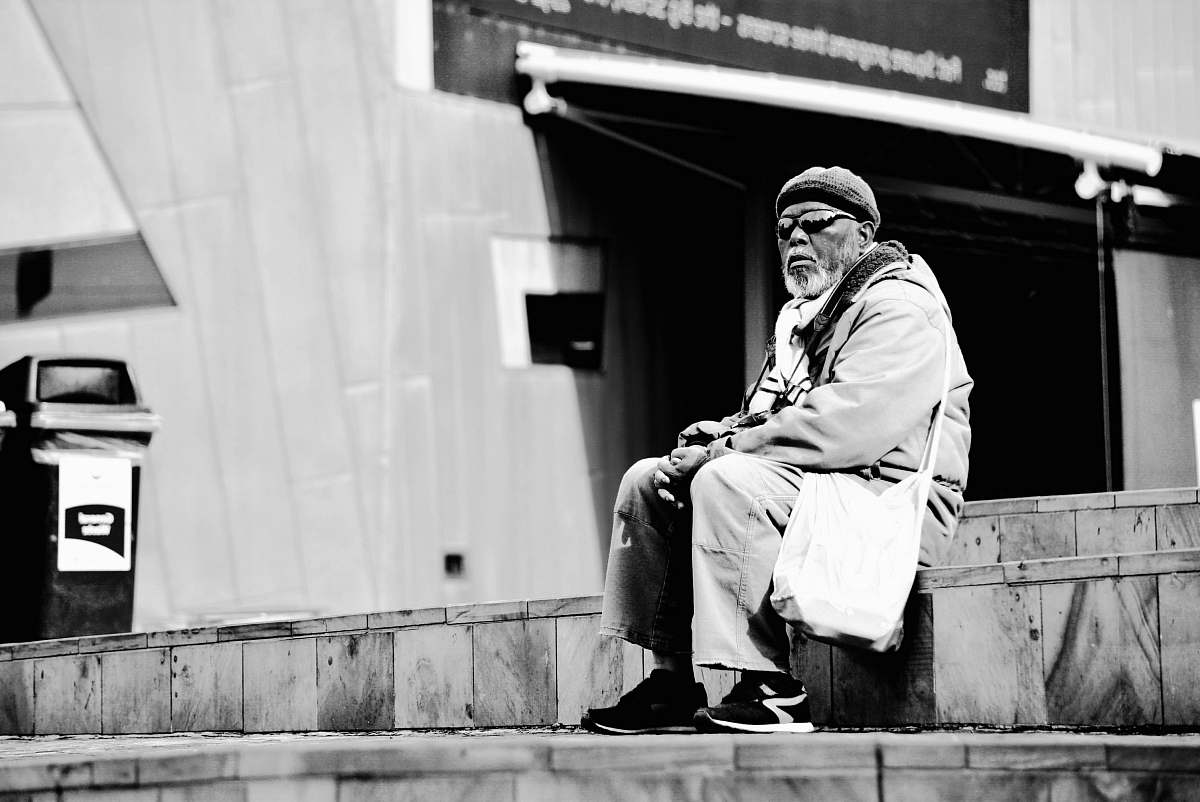 human greyscale photograpy of man sitting on gray stair black-and-white