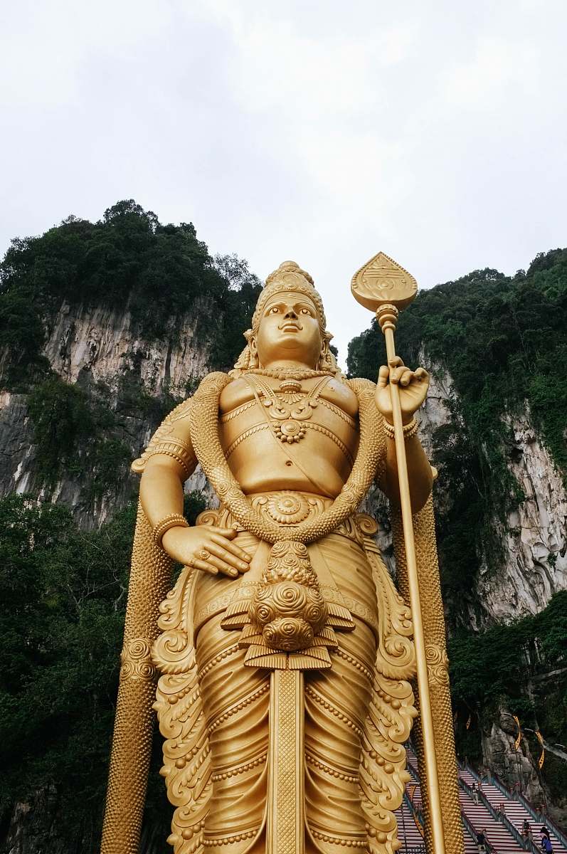 people low angle photograph of Lord Murugan state near mountain cliff under cloudy sky human