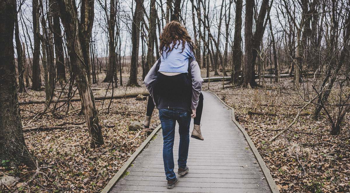 people man carrying a woman on his back in forest path human