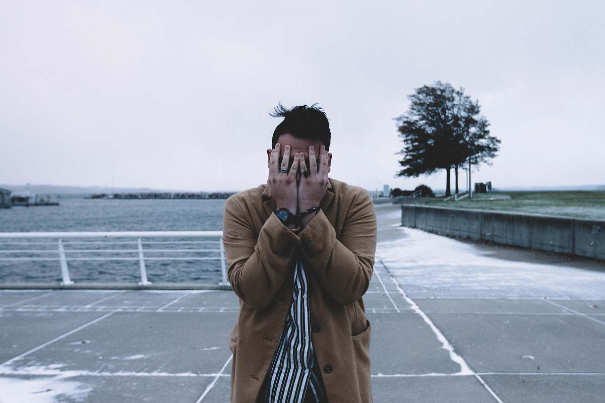 human man covering face during daytime people