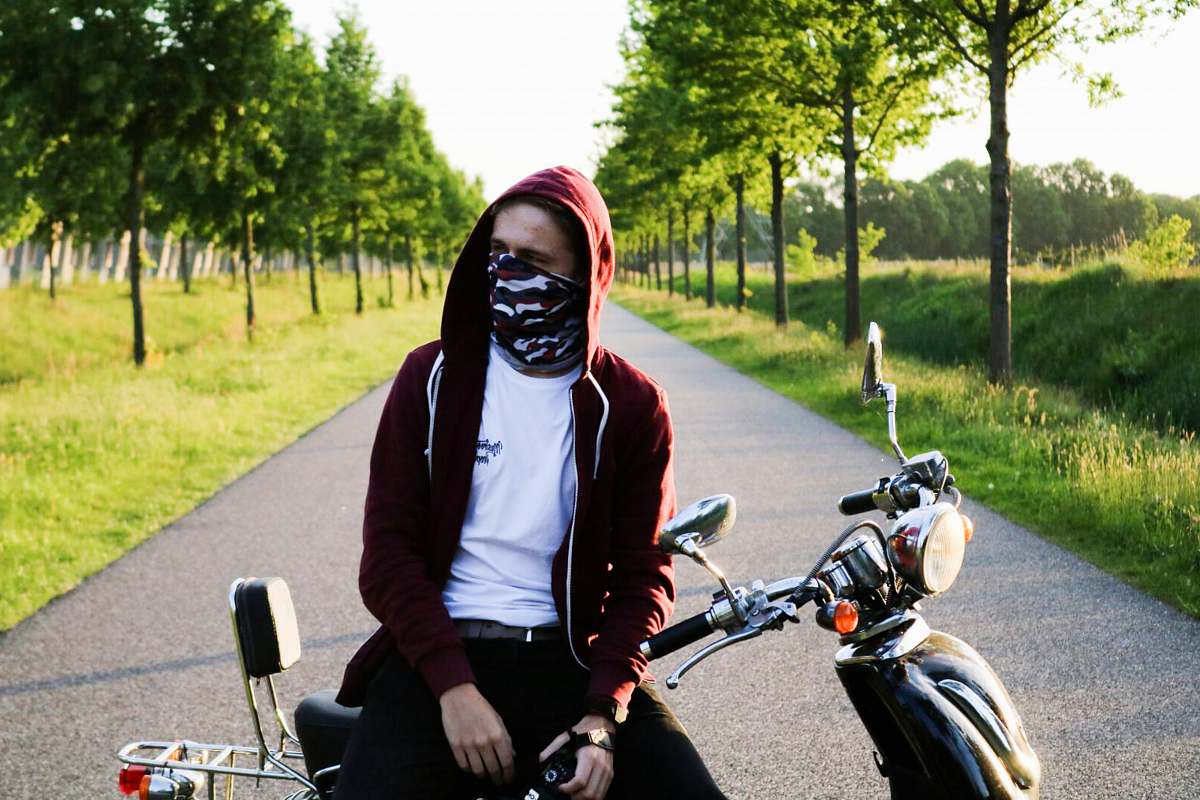 human man covering his face with bandanna sitting on motorcycle people
