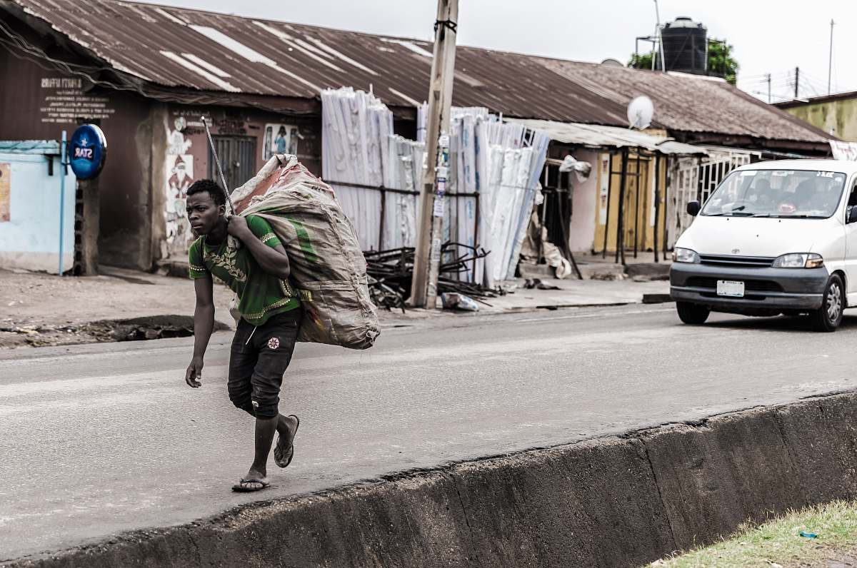 people man holding brown sack beside pave road human