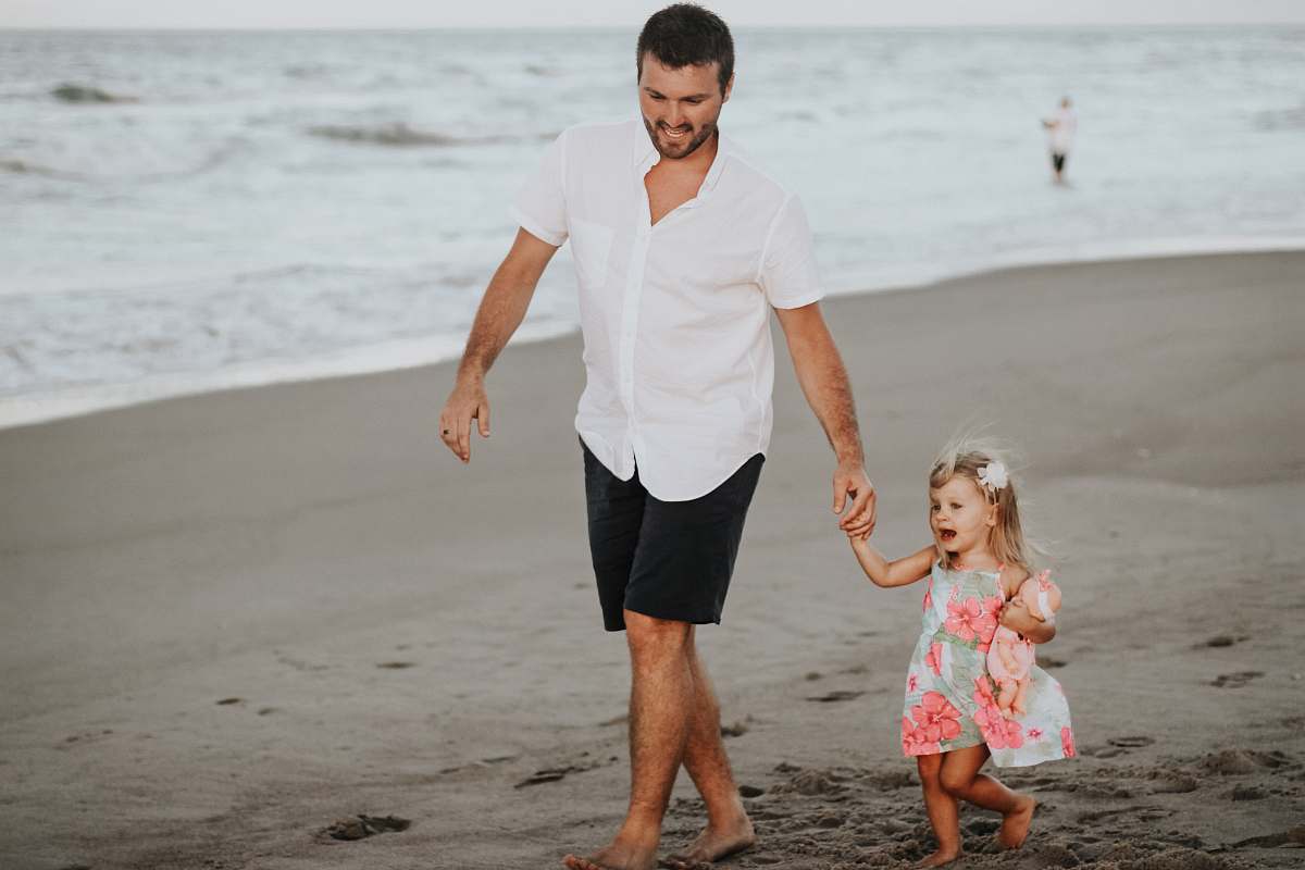 people man holding her daughter while walking at the coastline beach