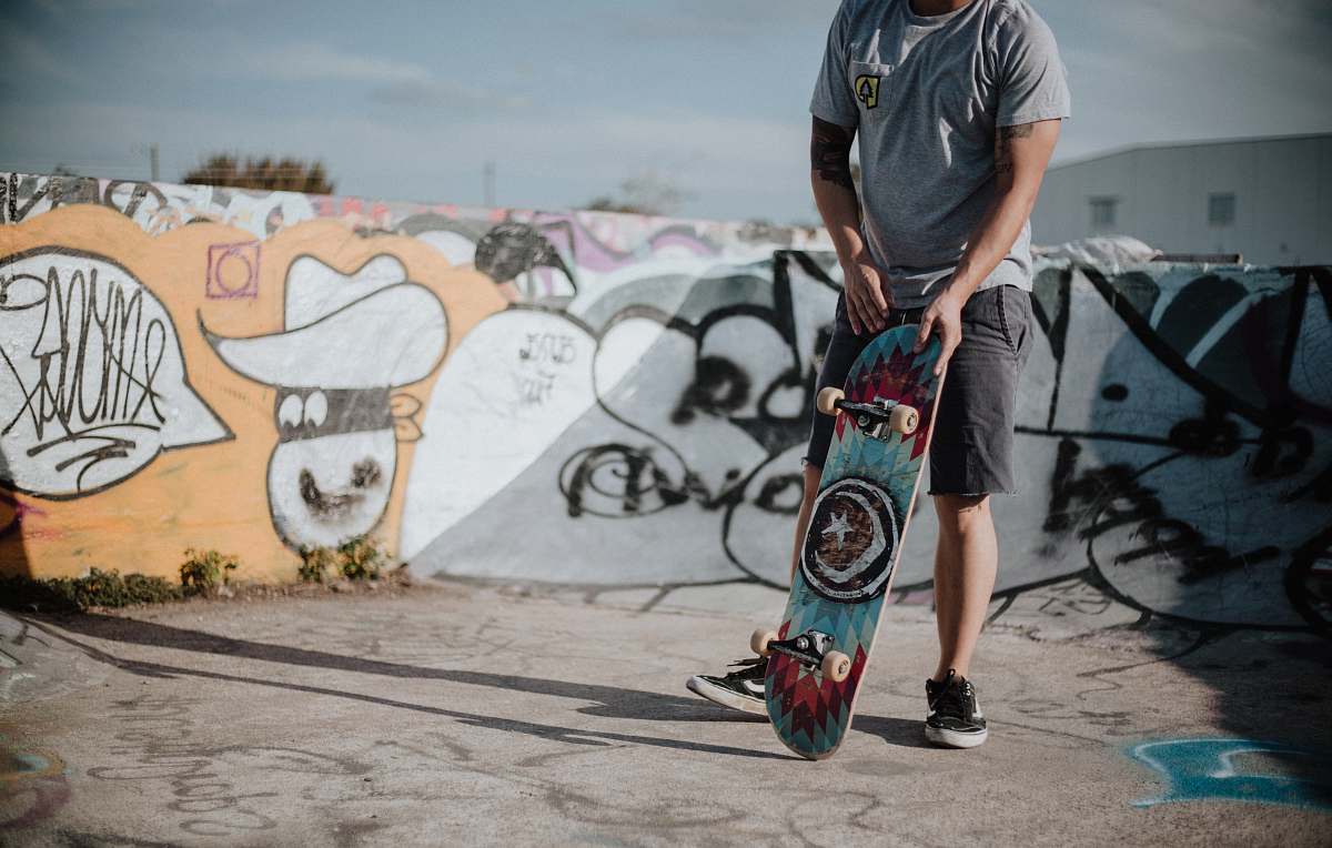 skateboard man holding teal and red skateboard sport