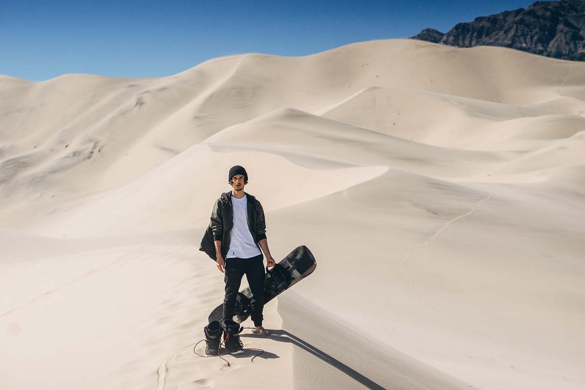 human man in black jacket standing on desert people