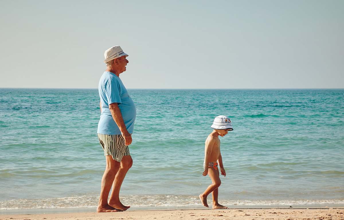 sea man in blue shirt standing on seashore near boy in white hat beach