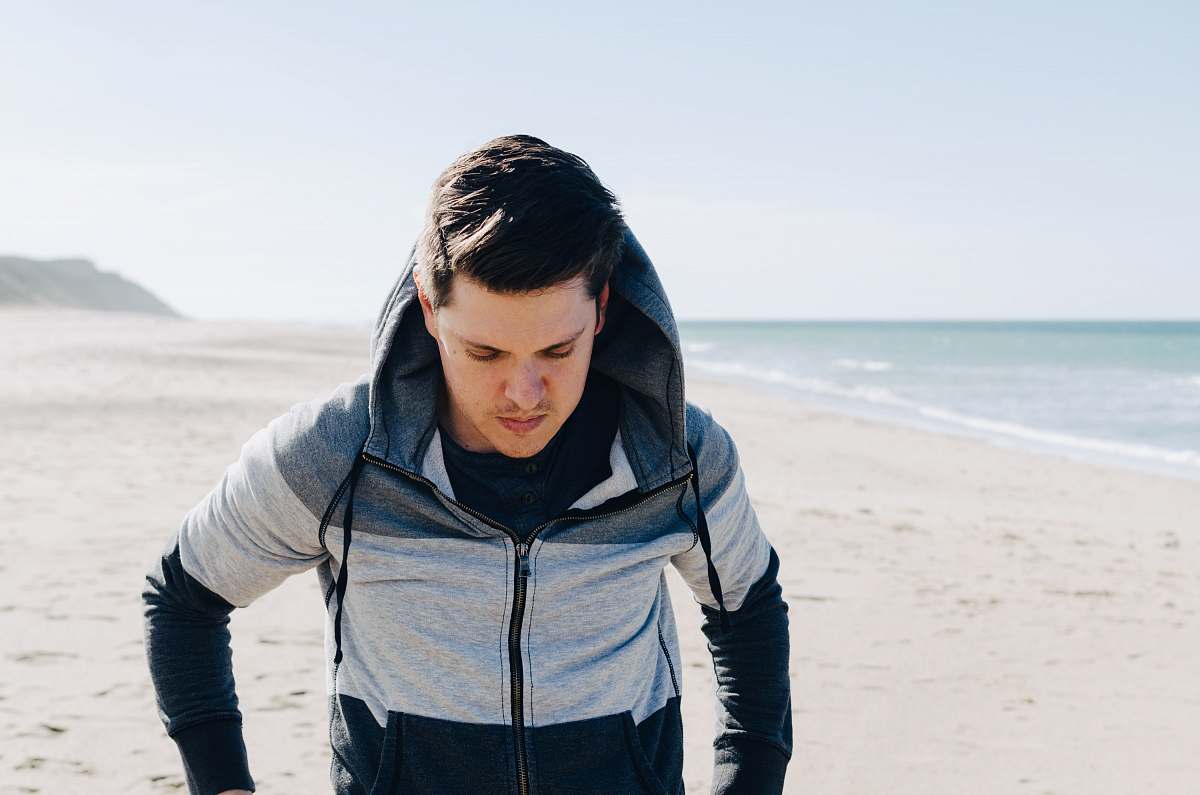 people man in gray and black zip-up hoodie walking beside ocean human