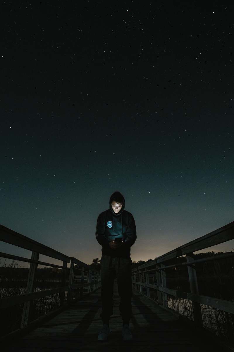 human man in the middle of bridge looking to his phone people