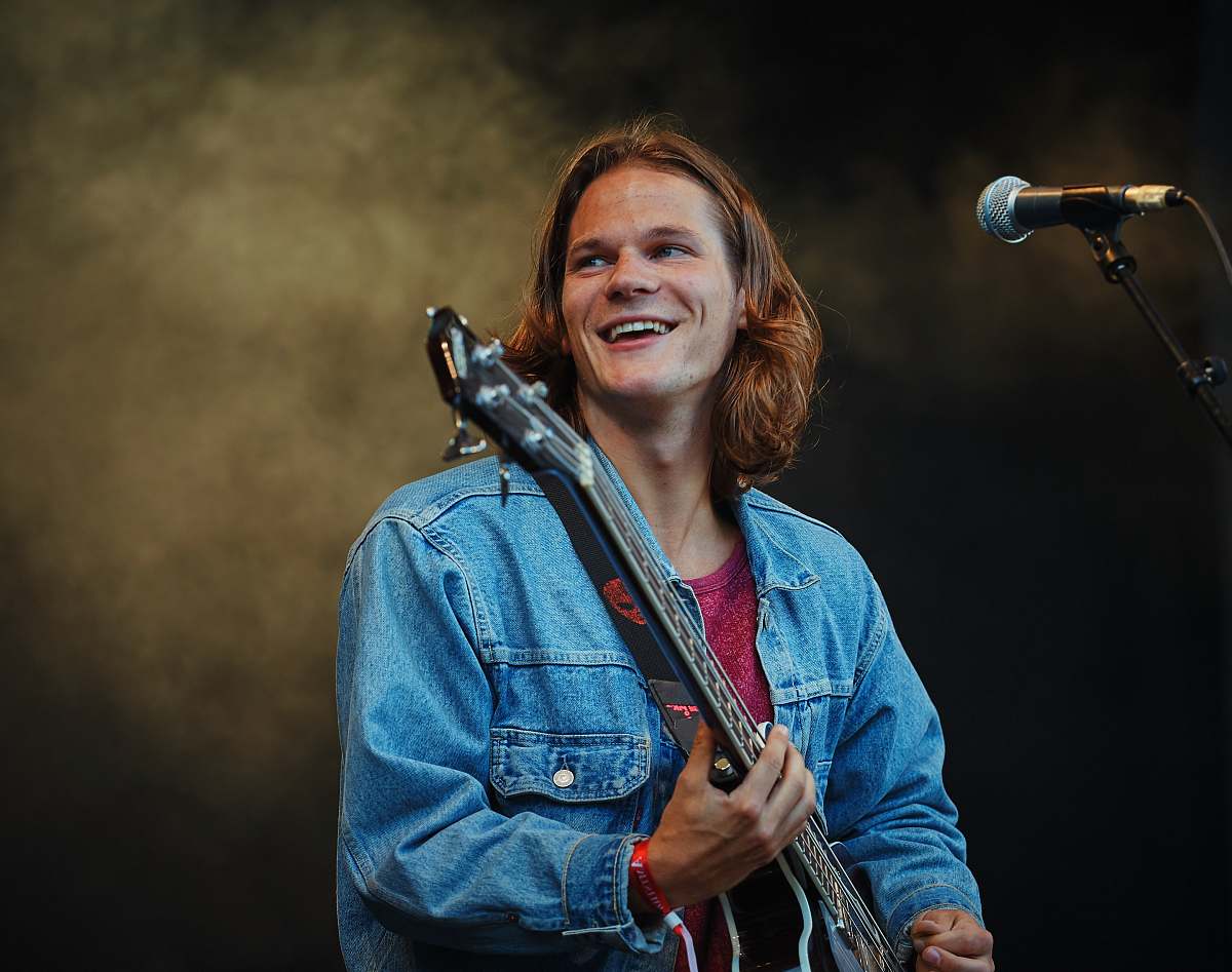 human man playing guitar while looking sideway people