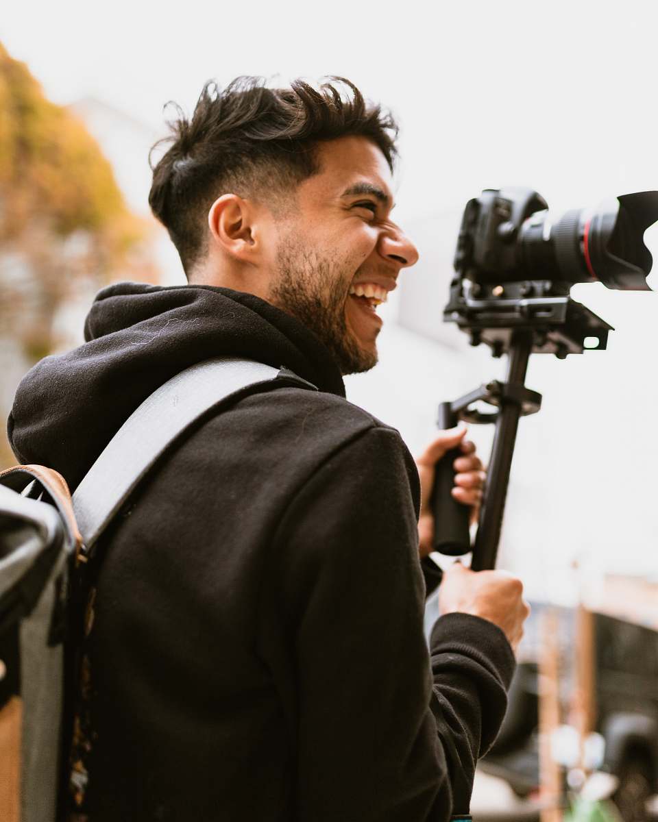 human man smiling while holding DSLR camera people