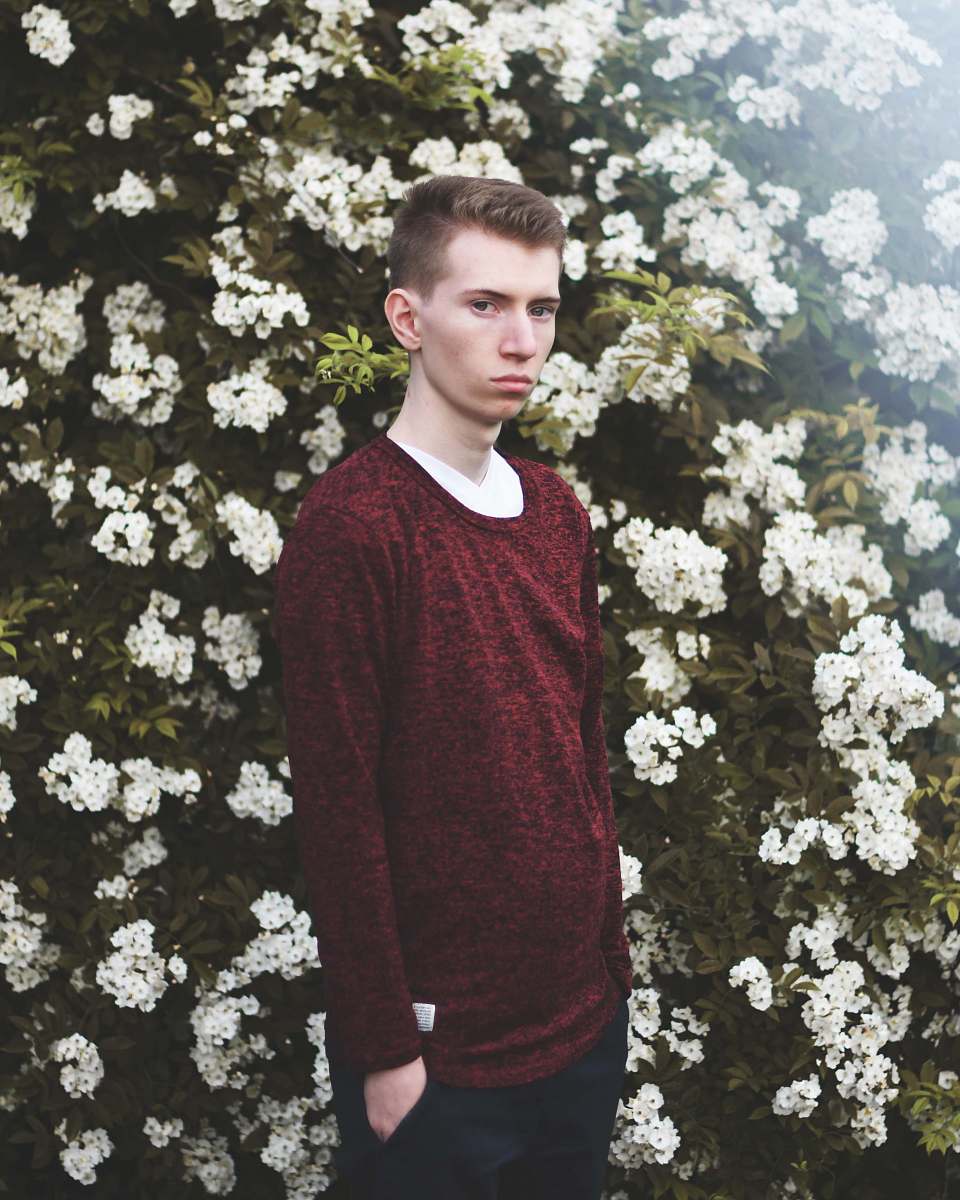 human man standing against white petaled flower bed people