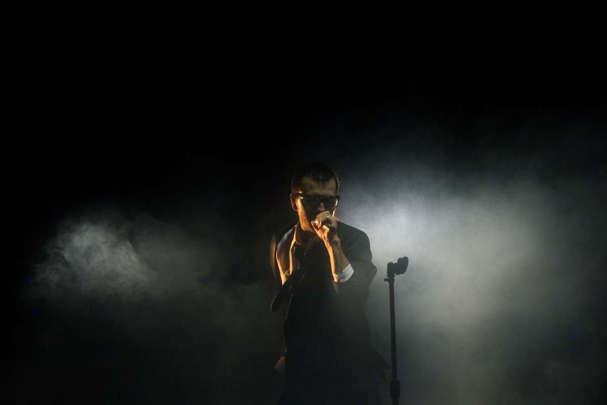 human man standing beside microphone stand holding microphone music