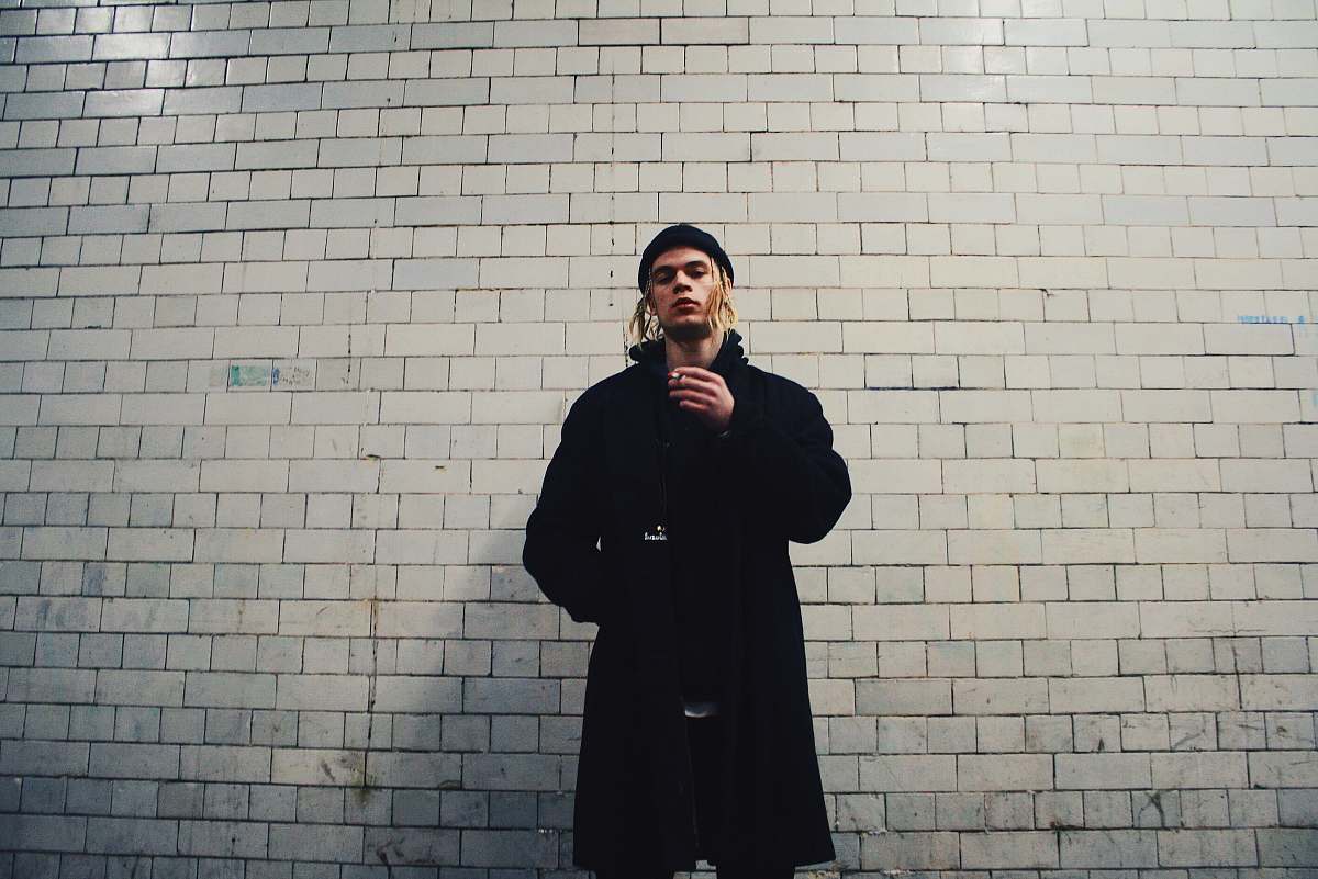 human man standing near gray brick wall people