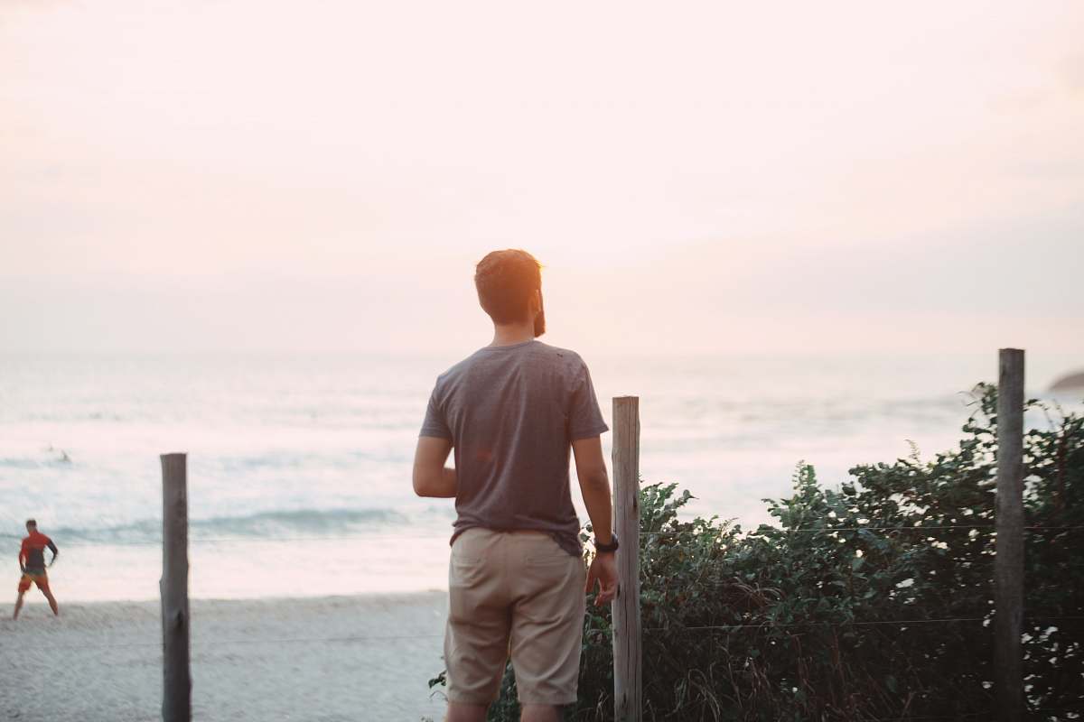 human man standing near post facing beach people